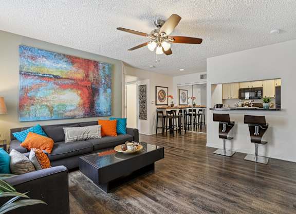 A living room with a grey couch and a painting on the wall.