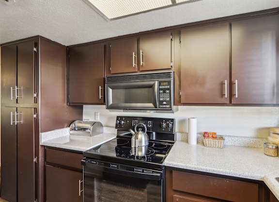 A kitchen with brown cabinets and a black stove top oven.