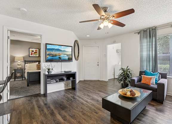 A modern living room with a dark wood floor and white walls.