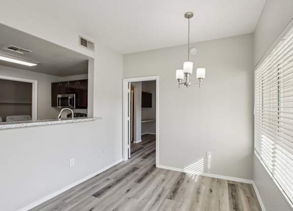 A room with a chandelier and a kitchen area in the background at Sweetwater At Metro North Apartments, Phoenix, AZ