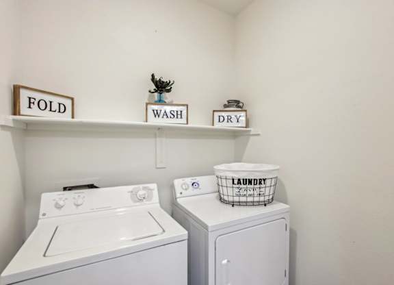 A laundry room with a washer and dryer and a laundry basket on top of the dryer at Sweetwater At Metro North Apartments, Phoenix, Arizona