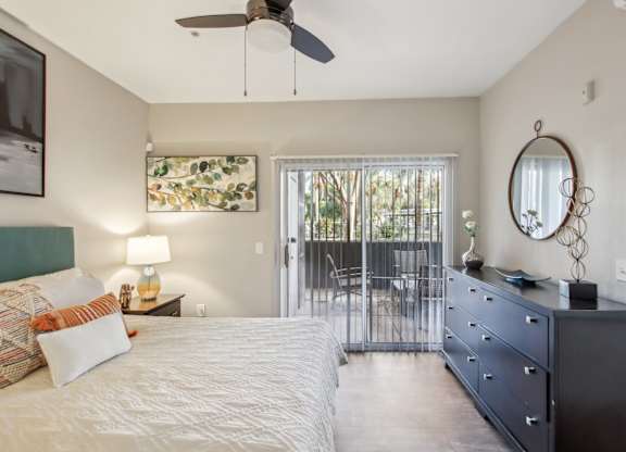 A bedroom with a bed, dresser, and a ceiling fan at Sweetwater At Metro North Apartments, Arizona 85029