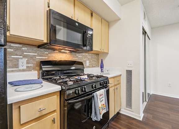 A kitchen with a black stove top oven and a black microwave above it.