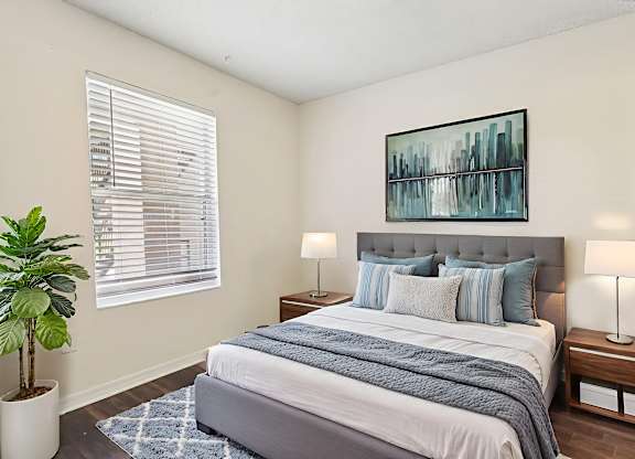 A bedroom with a large bed and a potted plant.
