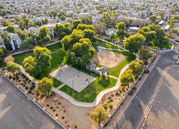 A basketball court is surrounded by trees and grass in a park at Sweetwater At Metro North Apartments, Arizona