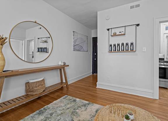 A kitchen with a wooden floor and a round mirror on the wall.