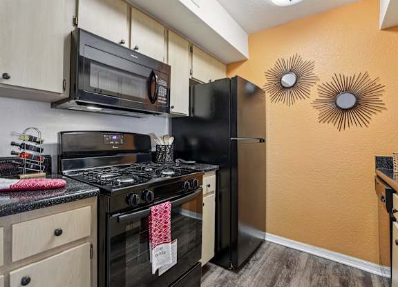 A kitchen with black appliances and wooden cabinets.