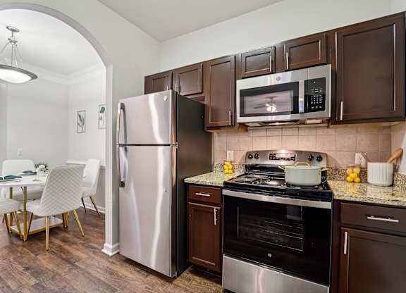 A kitchen with brown cabinets and a stainless steel refrigerator.