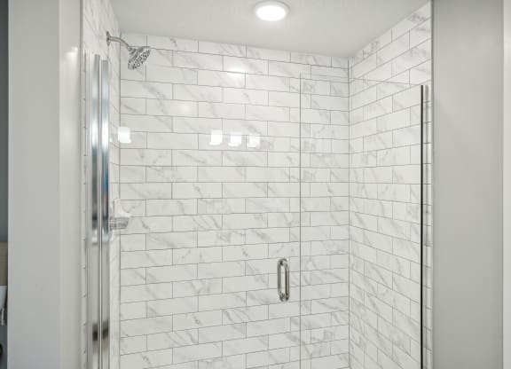 a large shower with white tile walls and a glass shower door at Edge75, Naples, Florida 34104