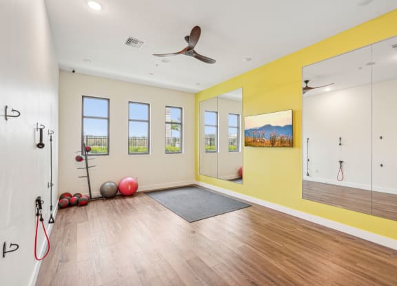 a workout room with a ceiling fan and mirrors on the wall at Edge75, Naples, Florida 34104