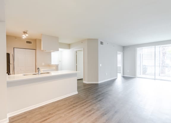 a kitchen and living room with hardwood floors and a sliding glass door to a balcony at Heritage Bay, Jensen Beach, FL