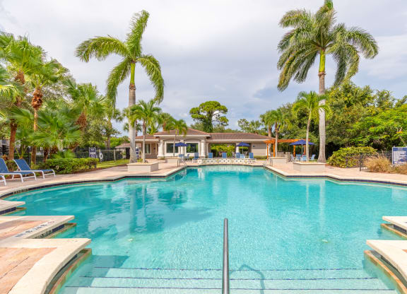 a large swimming pool with palm trees in the background at Heritage Bay, Jensen Beach, FL