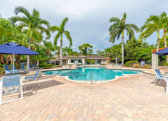 a large swimming pool with lounge chairs and umbrellas at Heritage Bay, Jensen Beach, 34957