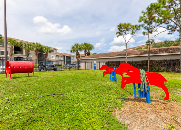 a playground with a red dog and a blue dog on a grassy field at Heritage Bay, Jensen Beach, 34957