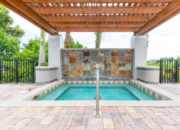 a swimming pool with a stone wall and a wooden pergola at Heritage Bay, Florida