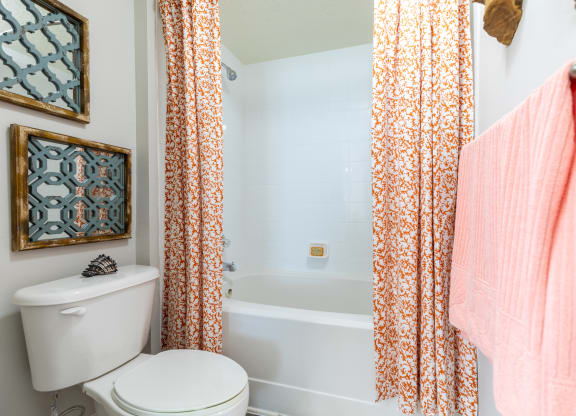 a bathroom with a white toilet next to a bathtub with a orange shower curtain at Heritage Bay, Florida, 34957