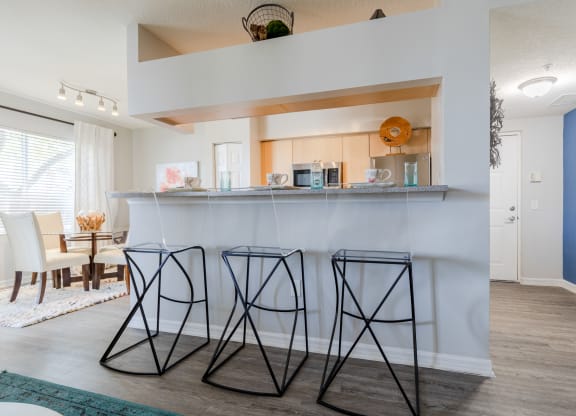 a kitchen with a bar and a dining room in the background at Heritage Bay, Jensen Beach, FL