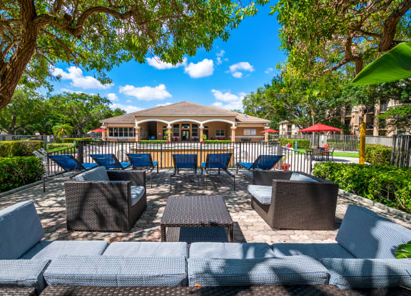 a patio with chairs and tables and a house in the background at Pembroke Pines Landings, Pembroke Pines, FL, 33025