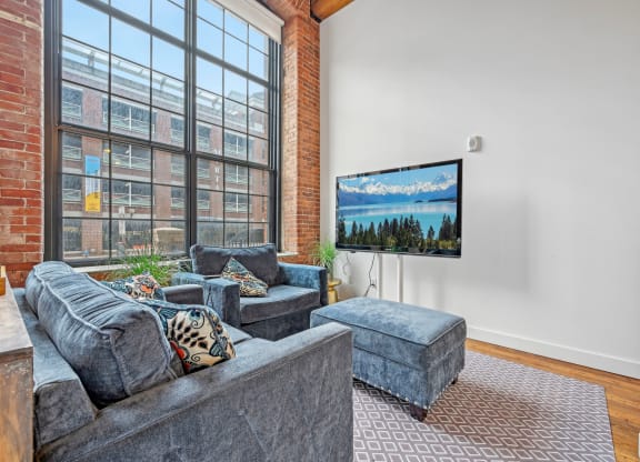 a living room with a large window and a couch and a chair at Riverwalk Apartments, Lawrence, MA