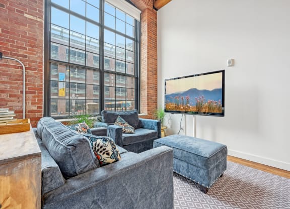 a living room with a large window and a couch and a chair at Riverwalk Apartments, Lawrence, MA