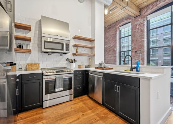 a kitchen with black and white cabinets and a large window at Riverwalk Apartments, Lawrence, MA