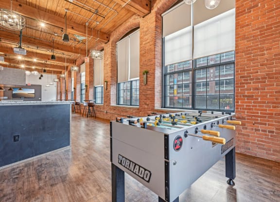 a foosball table in a room with brick walls and a bar at Riverwalk Apartments, Lawrence, MA