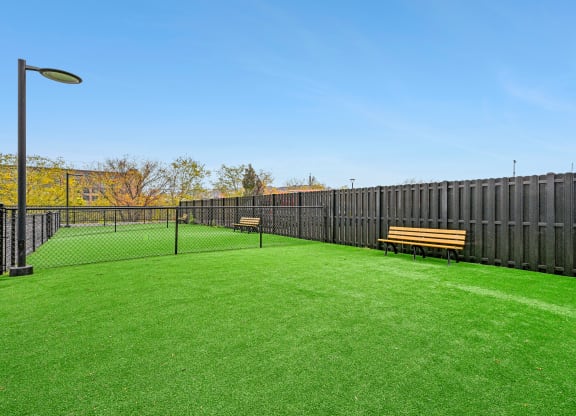 a yard with a tennis court and benches at Riverwalk Apartments, Lawrence, MA