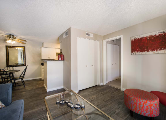 Living room with a glass coffee table and a red ottoman at Windmill Apartments, Colorado, 80916