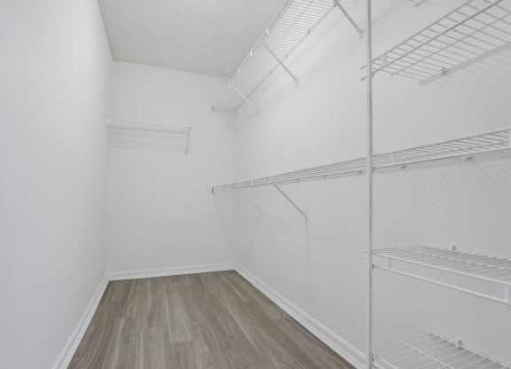 an empty room with white walls and wood flooring and a white closet with shelves at Pembroke Pines Landings, Pembroke Pines, Florida