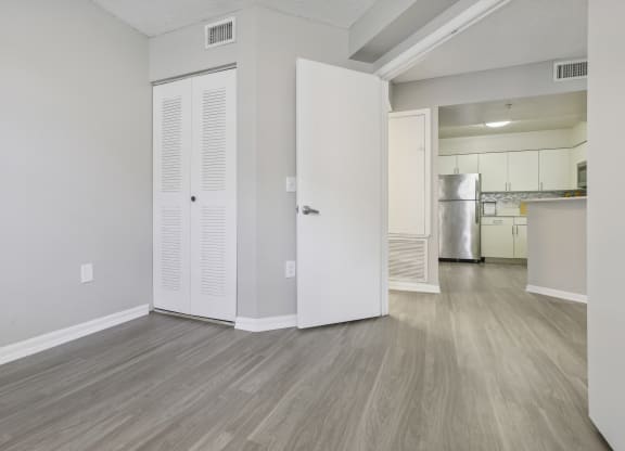 the living room and kitchen of an apartment with white walls and wood flooring at Pembroke Pines Landings, Pembroke Pines, Florida, 33025