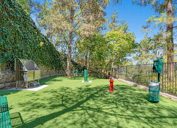 A green lawn with a red fire hydrant and a green trash can.