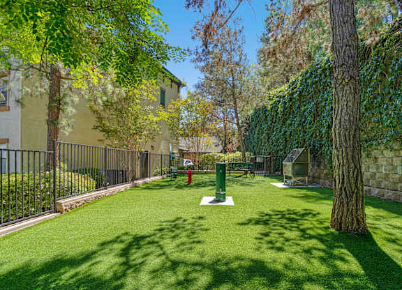 A green lawn with a tree and a red fire hydrant.