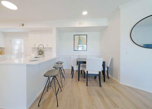 A kitchen with white cabinets and a white island with a bar stool.