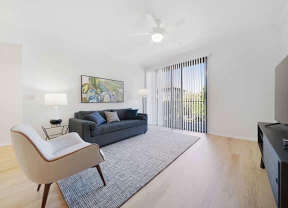 A living room with a grey couch, a white chair, and a painting on the wall.