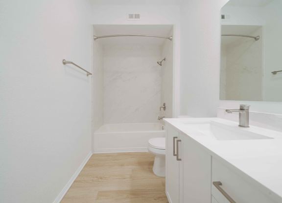 A white bathroom with a toilet, sink, and bathtub.