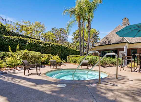 A pool surrounded by a patio with chairs and a table.