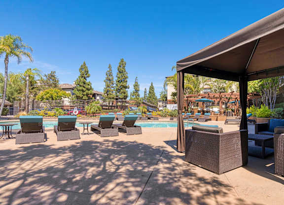 A poolside area with lounge chairs and a canopy.