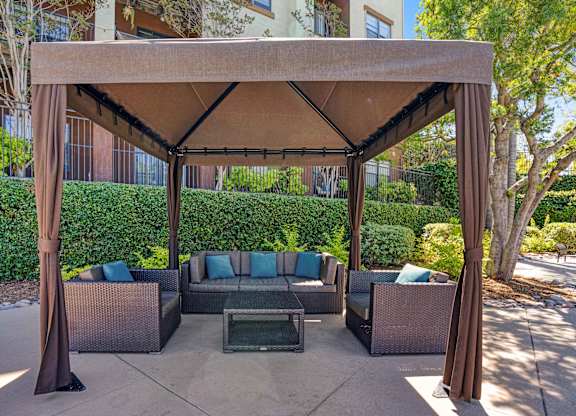 A patio with a couch and a table under a canopy.