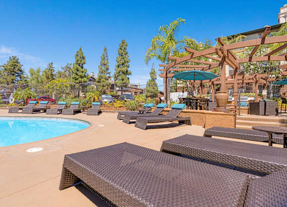 A pool area with sun loungers and a shaded seating area.