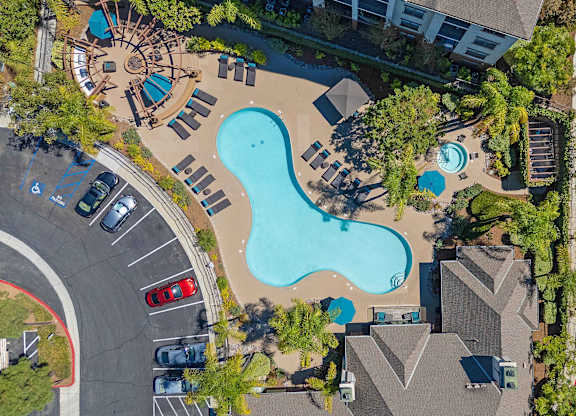 An aerial view of a swimming pool surrounded by trees and buildings.