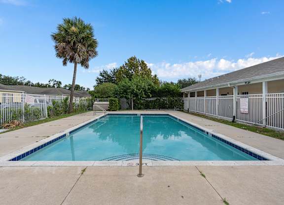 a swimming pool with a palm tree in front of a building at The Groves at Wimauma Apartments , Wimauma, 33598