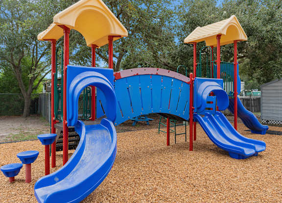 a playground with a blue slide and a yellow and red structure at The Groves at Wimauma Apartments , Florida
