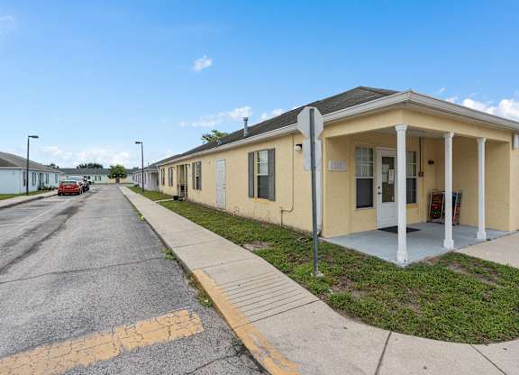 a yellow building with a sidewalk and a street at The Groves at Wimauma Apartments , Florida
