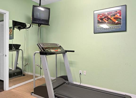 a treadmill in a gym with a tv on the wall at The Groves at Wimauma Apartments , Wimauma, FL