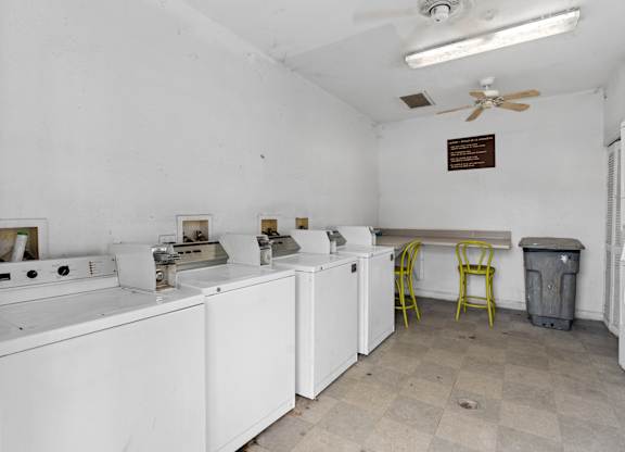 an empty room with white appliances and a yellow chair at The Groves at Wimauma Apartments , Wimauma, FL, 33598