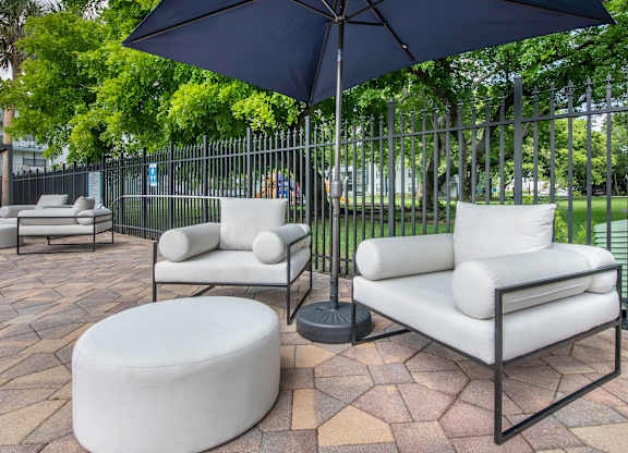 a patio with two white couches and two black umbrellas  at Club at Emerald Waters, Florida