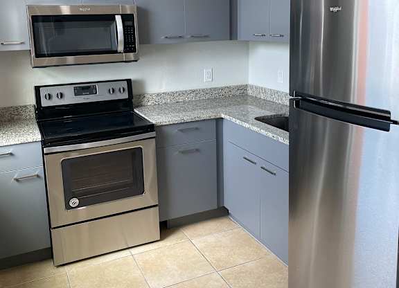 a kitchen with gray cabinets and stainless steel appliances at Colonial Drive Apartments, Orlando, FL