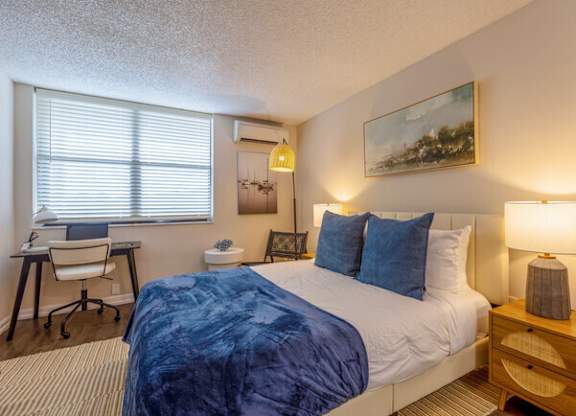 a bedroom with a bed and a desk with a chair  at Club at Emerald Waters, Hollywood, 33021