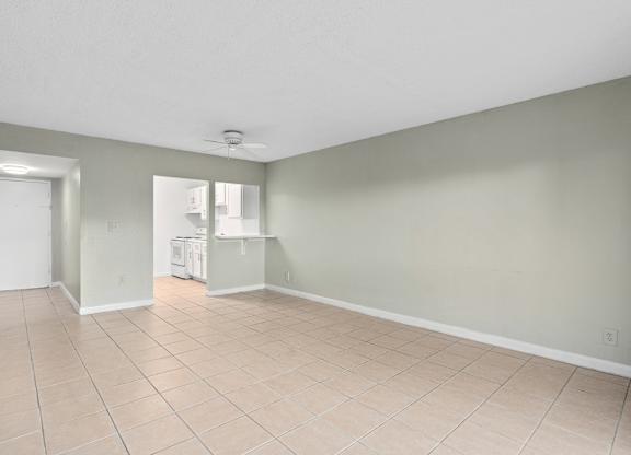 the living room and kitchen of an empty house with a tiled floor at Cypress Grove, Lauderhill, 33313