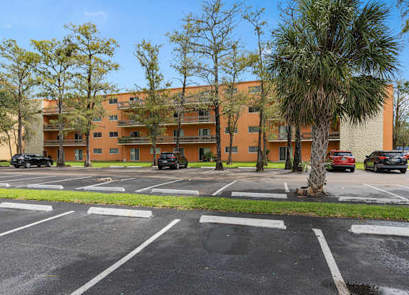 an apartment building with a parking lot and palm trees at Cypress Grove, Florida